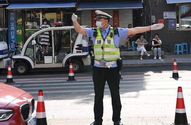 Foto/CFP: Një punonjës i policisë rrugore liron trafikun për nxënësit që shkojnë për në provimin kombëtar të pranimit në universitet në provincën Anhui të Kinës, 7 qershor 2022.