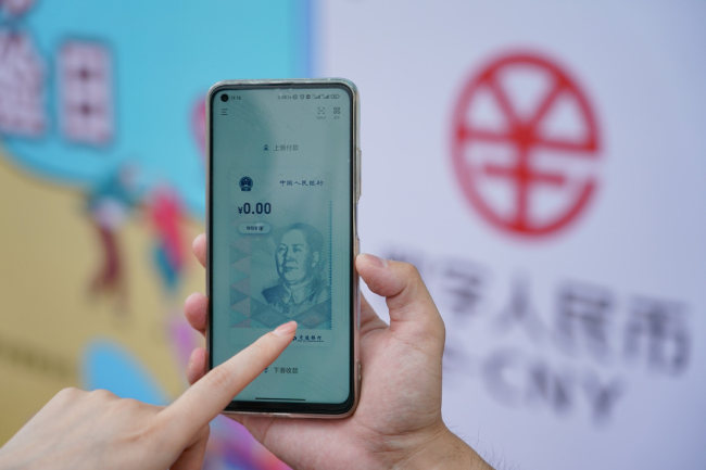 Një anëtar i stafit të Degës së Bankës së Komunikimeve në Pekin hapë një portofol dixhital RMB në një telefon celular,më 16 qershor të vitit 2021. Xinhua