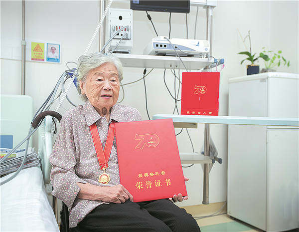 Η Λι επιδεικνύει το τιμητικό πιστοποιητικό της «μαχήτριας» από το Τμήμα Δημοσιότητας της Κεντρικής Επιτροπής του Κομμουνιστικού Κόμματος της Κίνας και άλλα τμήματα το 2019. [Φωτογραφία που δόθηκε στην China Daily]