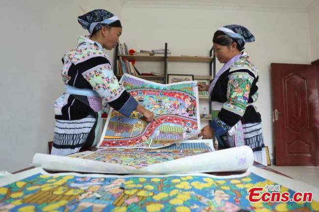 Δύο ζωγράφοι της εθνότητας των Μιάο τακτοποιούν ζωγραφικά έργα, στο χωριό Πινγκπό της κομητείας Λονγκλί της Αυτόνομης Νομαρχίας Τσιεννάν Μπουγί και Μιάο, στην επαρχία Γκουιτζόου της νοτιοδυτικής Κίνας, στις 15 Σεπτεμβρίου 2021