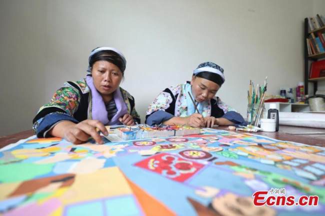 Δύο ζωγράφοι (画家Huàjiā ) της εθνότητας των Μιάο ζωγραφίζουν σύμφωνα με το στυλ των Μιάο στο χωριό Πινγκπό της κομητείας Λονγκλί της Αυτόνομης Νομαρχίας Τσιεννάν Μπουγί και Μιάο, στην επαρχία Γκουιτζόου της νοτιοδυτικής Κίνας, στις 15 Σεπτεμβρίου 2021.