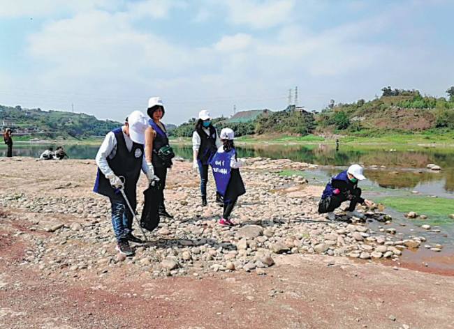 Εθελοντές μαζεύουν σκουπίδια κατά μήκος του ποταμού Τσισούι στο Λουτζόου. (Φωτογραφία / China Daily)