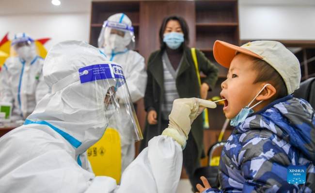 Ιατρικό προσωπικό παίρνει δείγμα από ένα παιδί σε ένα προσωρινό σημείο για τεστ νουκλεϊκού οξέος (核酸检测: hésuān jiǎncè) νέου κορονοϊού (新冠肺炎: Xīnguān fèiyán), στο Χοχότ, αυτόνομη περιοχή της Εσωτερικής Μογγολίας στην βόρεια Κίνα, 24 Οκτωβρίου 2021.