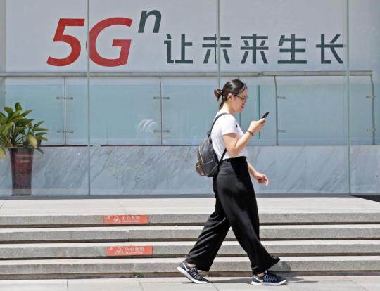 Μια γυναίκα περνά μπροστά από μια διαφημιστική πινακίδα για το δίκτυο 5G στο Πεκίνο, στις 3 Ιουνίου 2019. [Φωτογραφία/Xinhua]