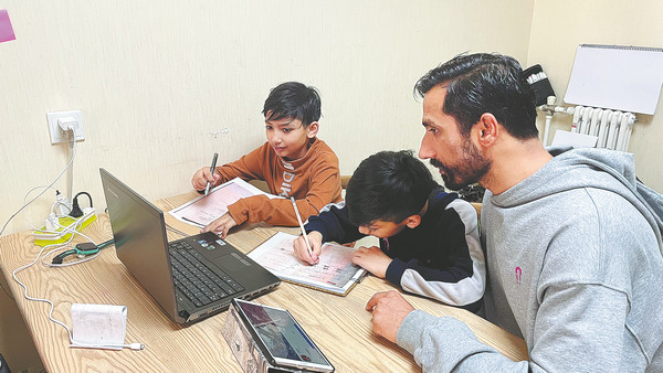 Ο εστιάτορας Ντεβ Ρατούρι βοηθά τα παιδιά του με τις εργασίες τους στο σπίτι τους στο Σι’αν στην επαρχία Σαανσί, στις 27 Δεκεμβρίου. [Φωτογραφία/Xinhua]