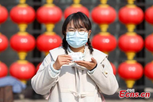 Επιβάτης δείχνει τα εισιτήριά της για το τρένο έξω από τον σιδηροδρομικό σταθμό Ναντσάνγκ στην επαρχία Τζιανγκσί της ανατολικής Κίνας, 3 Ιανουαρίου 2021. (Φωτογραφία/China News Service)