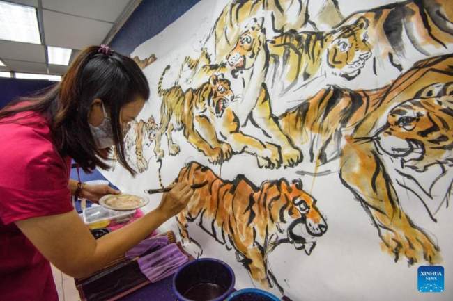 Ένας ζωγράφος δημιουργεί πίνακες με τίγρεις στην πολιτεία Κλανγκ του Σελανγκόρ στην Μαλαισία, στις 30 Δεκεμβρίου 2021. (Φωτογραφία Chong Voon Chung/Xinhua)