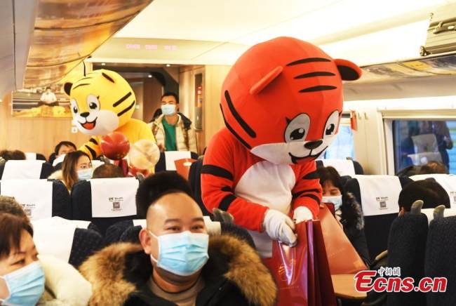 Οι συνοδοί του τρένου με στολές τίγρης (老虎: lǎohǔ) προσφέρουν δώρα στους επιβάτες, στο Τσονγκτσίνγκ, νοτιοδυτική Κίνα, στις 17 Ιανουαρίου 2022.