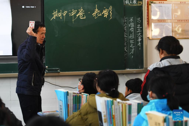 Ο Λου Γουεντζιάν κάνει ερωτήσεις στους μαθητές γυρίζοντας τραπουλόχαρτα στο σχολείο του Σανγκτσιό, στην επαρχία Χενάν της κεντρικής Κίνας, 2 Δεκεμβρίου 2021. (Xinhua/Zhang Haoran)