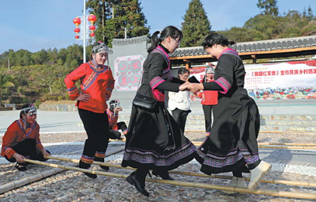 Χωρικοί της εθνότητας Σε, χορεύουν πάνω από μπαμπού μαζί με επισκέπτες στην πόλη Ντονγκτόου του Χουιτσάνγκ, στην επαρχία Τζιανγκσί. [Φωτογραφία /CHINA DAILY]