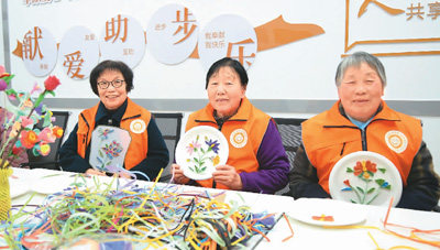 Η Μα Γιουμέι (αριστερά) και άλλοι ηλικιωμένοι εθελοντές επιδεικνύουν χειροτεχνήματα προς δωρεά. (Φωτογραφία/Li Le)