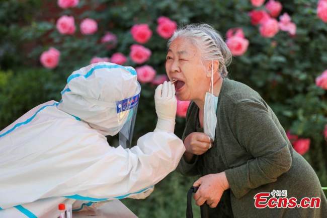 Ιατρός λαμβάνει δείγμα με μπατονέτα από μια γυναίκα για δοκιμή νουκλεϊκού οξέος στην συνοικία Σανλιτούν της περιοχής Τσαογιάνγκ στην πρωτεύουσα της Κίνας, στις 15 Μαΐου 2022. (Φωτογραφία: China News Service) 