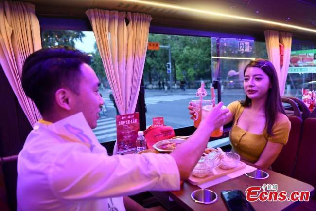 Πελάτες απολαμβάνουν χότποτ, το αγαπημένο πιάτο του Σιτσουάν, πάνω σε ένα λεωφορείο τουριστικής περιήγησης, βλέποντας συγχρόνως τα αξιοθέατα του Τσενγκντού, στην επαρχία Σιτσουάν της νοτιοδυτικής Κίνας, 19 Μαΐου 2022. (Φωτογραφία: China News Service)