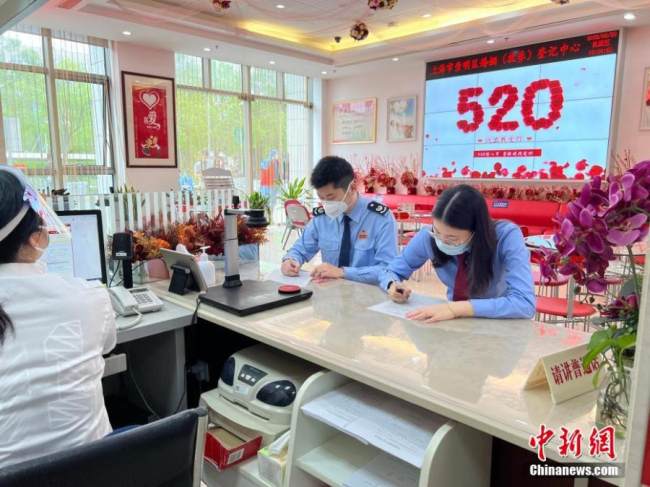 Ένα ζευγάρι με ειδικές στολές υπηρεσίας εγγράφεται σε ένα κέντρο εγγραφής γάμων στην περιοχή Τσαομίνγκ, στη Σαγκάη της ανατολικής Κίνας, 20 Μαΐου 2022. (Φωτογραφία: China News Service) 