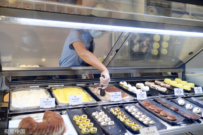 Μια εργαζόμενη βάζει παγωτό στους πελάτες στο κατάστημα παγωτών Moutai στο Χουαϊρέν, στην επαρχία Γκουιτζόου, στις 20 Μαΐου 2022. [Φωτογραφία/VCG] 
