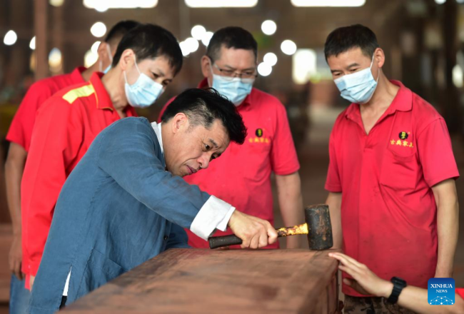 Ο Τσεν Γιουσού (μπροστά) επιδεικνύει δεξιότητες συναρμολόγησης επίπλων σε ένα εργαστήριο κατασκευής επίπλων στο Πουτιέν, στην επαρχία Φουτζιέν της νοτιοανατολικής Κίνας, 10 Ιουνίου 2022.