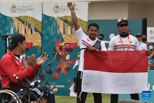 Ο Σετιάουαν (κέντρο) της Ινδονησίας πανηγυρίζει με τον προπονητή του μετά τη νίκη του αγώνα για το χρυσό μετάλλιο στην Ατομική Τοξοβολία Ανδρών σε αγώνα με τον Hanreuchai Netsiri της Ταϊλάνδης στους Αγώνες ASEAN Para Games 2022 στη Σουρακάρτα της Ινδονησίας, 3 Αυγούστου 2022. (Xinhua/Agung Kuncahya B.)