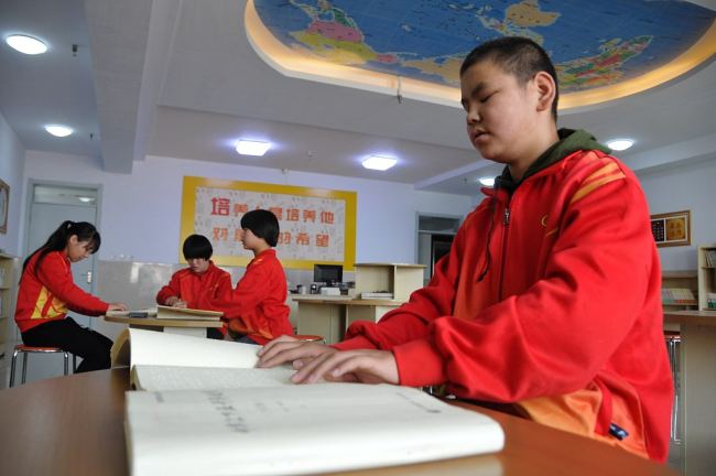 Un elev dintr-o școală pentru copii nevăzători din provincia Hebei citesc o carte editată în alfabetul Braille.